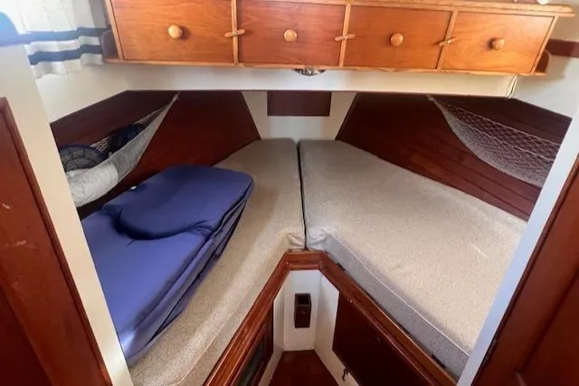 Slide: The Image of 1980 Grand Banks 32 Flybridge Trawler cabin with twin beds and wooden storage drawers. - 12