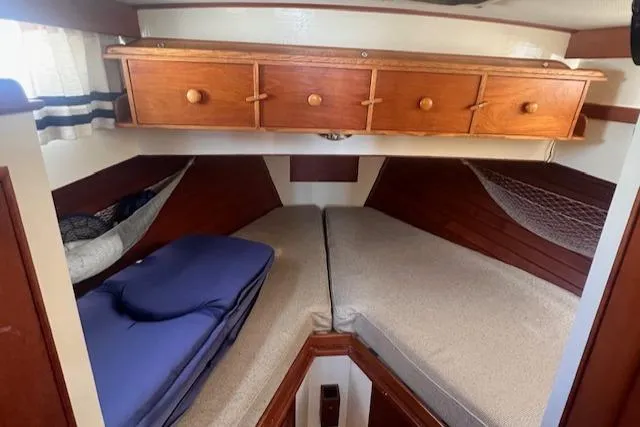 Slide: The Image of 1980 Grand Banks 32 Flybridge Trawler cabin with twin beds and wooden storage cabinets. - 13