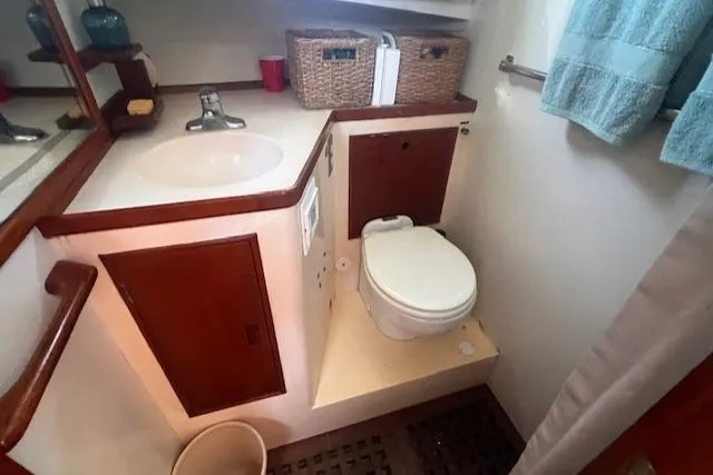 Slide: The Image of 1980 Grand Banks 32 Flybridge Trawler bathroom with sink, toilet, and storage baskets. - 14