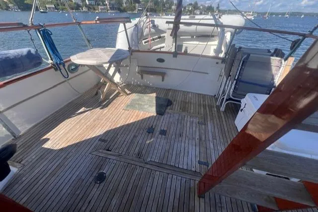 Slide: The Image of 1980 Grand Banks 32 Flybridge Trawler deck with wooden flooring and seating, overlooking a scenic harbor. - 21