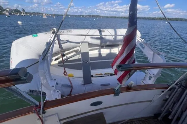 Slide: The Image of 1980 Grand Banks 32 Flybridge Trawler with dinghy and American flag on calm water. - 23