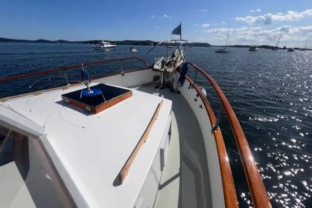 Slide: The Image of 1980 Grand Banks 32 Flybridge Trawler on calm waters, showcasing deck and railing. - 27