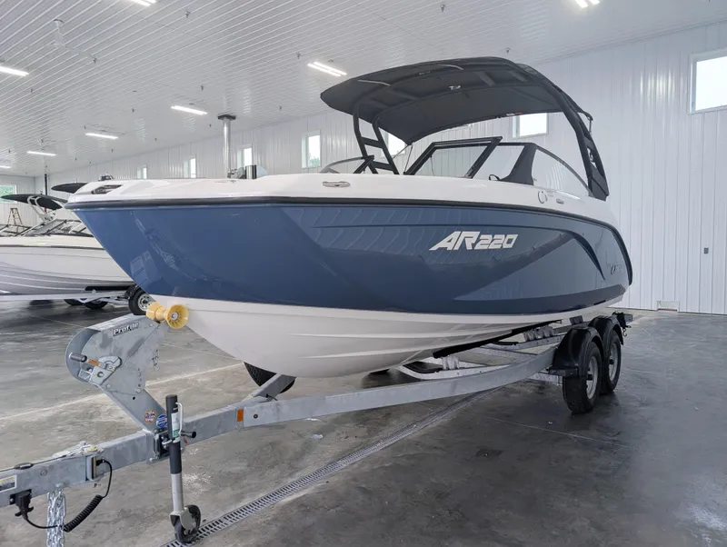 Slide: The Image of 2025 Yamaha Boats AR220 in showroom, blue and white design on trailer. - 4
