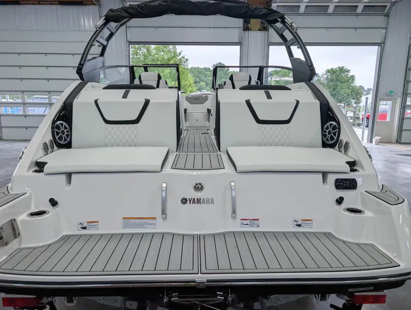 Slide: The Image of 2025 Yamaha Boats 222SE, rear view in a garage, showcasing seating and speakers. - 11