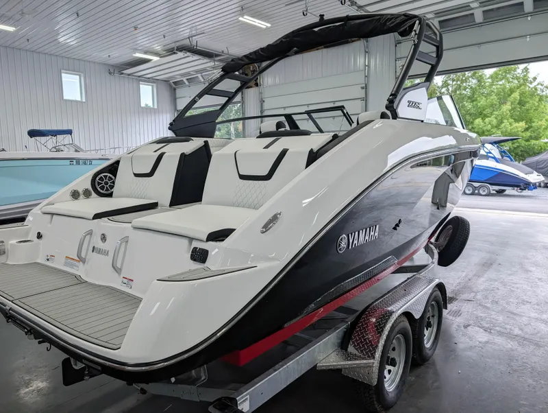 Slide: The Image of 2025 Yamaha Boats 222SE on trailer in a showroom, featuring sleek design and modern amenities. - 13