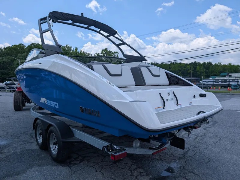 Slide: The Image of 2025 Yamaha AR250 boat on trailer, blue and white design, parked outdoors. - 5