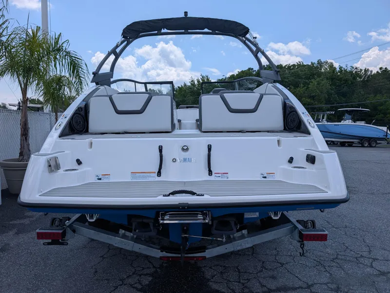 Slide: The Image of 2025 Yamaha Boats AR250, rear view, on trailer, with palm tree and blue sky background. - 6