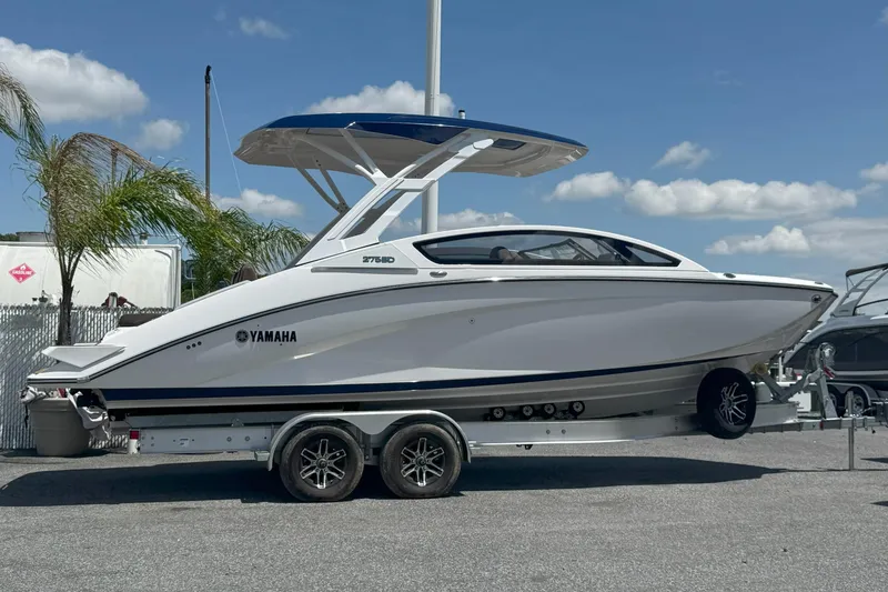 The Image of 2025 Yamaha Boats 275SD on trailer, sleek design, parked outdoors under blue sky. - 0