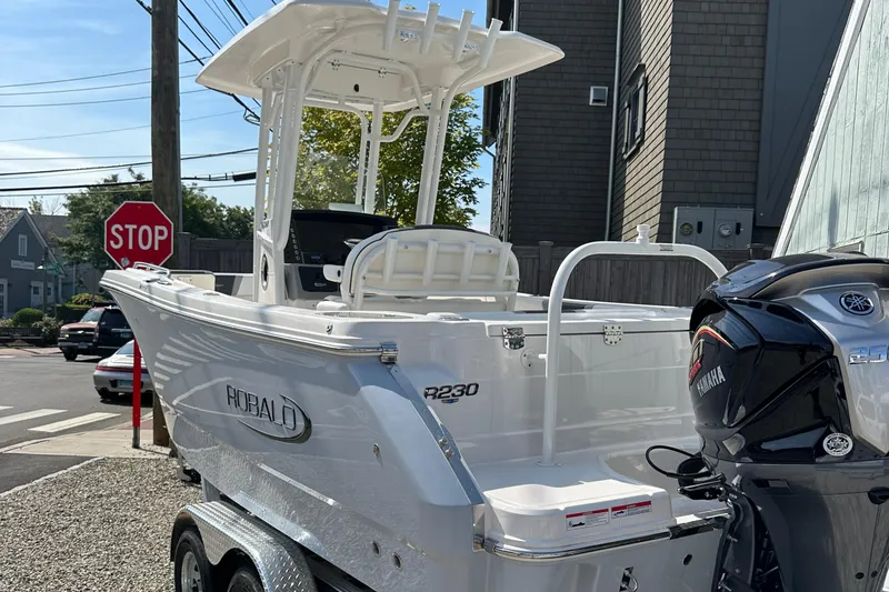 Slide: The Image of 2025 Robalo R230 Center Console boat on trailer, parked near a stop sign. - 3