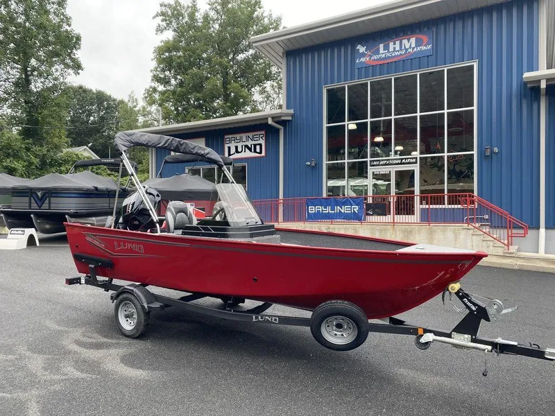 Slide: The Image of 2025 Lund 1650 Angler boat in red, parked outside a marine dealership. - 2