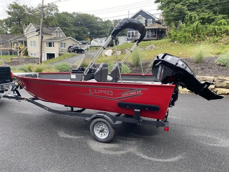 Slide: The Image of 2025 Lund 1650 Angler boat, red, on trailer, parked in residential area. - 4