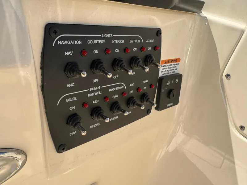 Slide: The Image of Control panel of 2025 Scout 215 Dorado boat with labeled switches and warning label. - 12