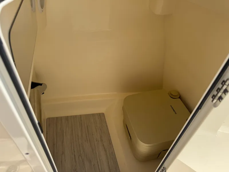 Slide: The Image of 2025 Scout 215 Dorado boat interior with portable toilet and wooden flooring. - 13