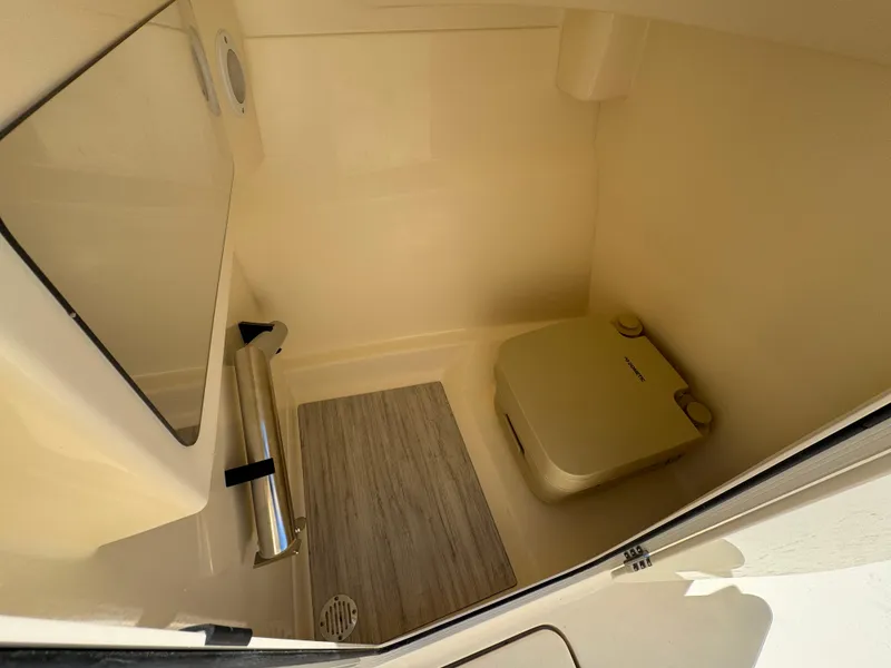 Slide: The Image of Interior of 2025 Scout 215 Dorado boat with compact toilet and wooden flooring. - 14
