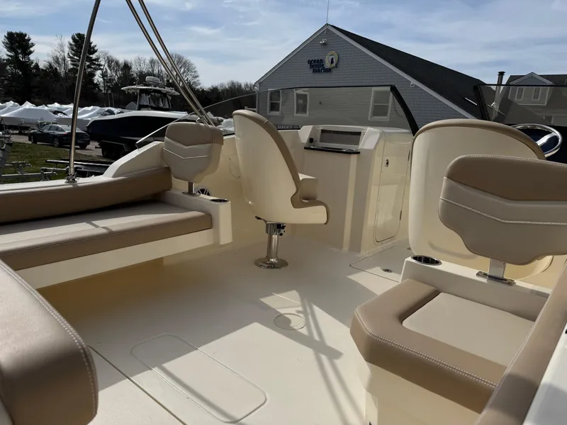Slide: The Image of 2025 Scout 215 Dorado boat interior with beige seating and helm, under a clear sky. - 21
