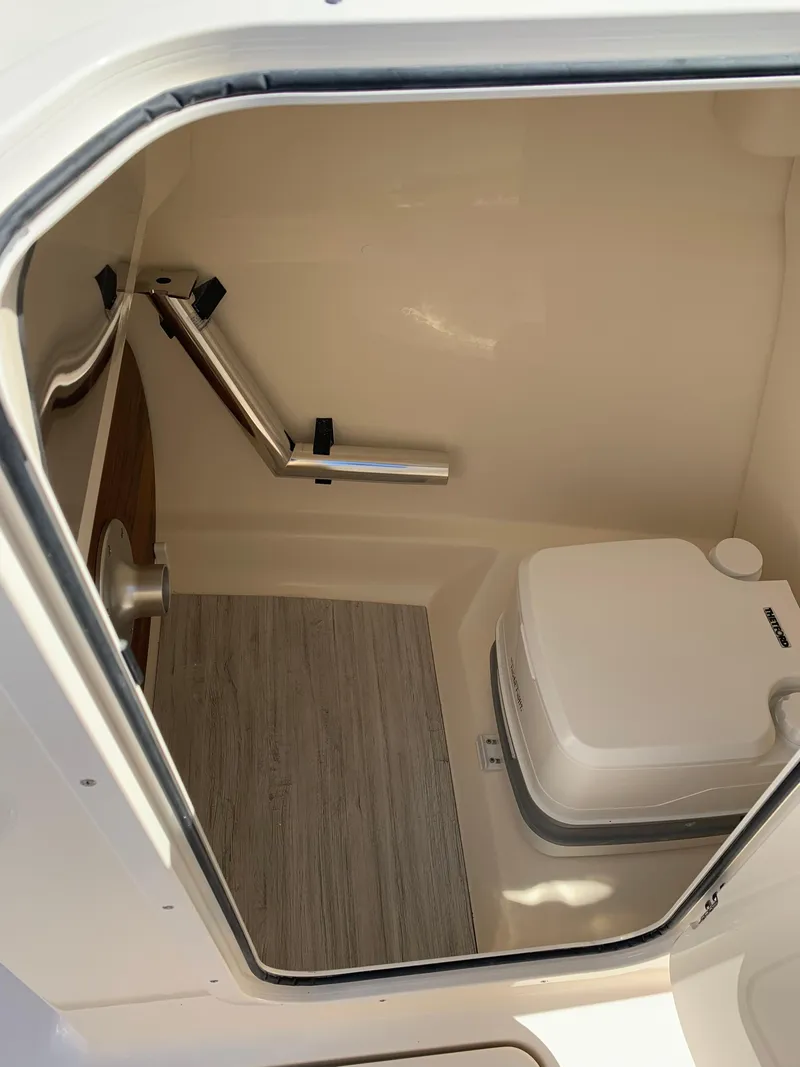 Slide: The Image of 2025 Scout 215 Dorado boat interior with compact toilet and wooden flooring. - 28