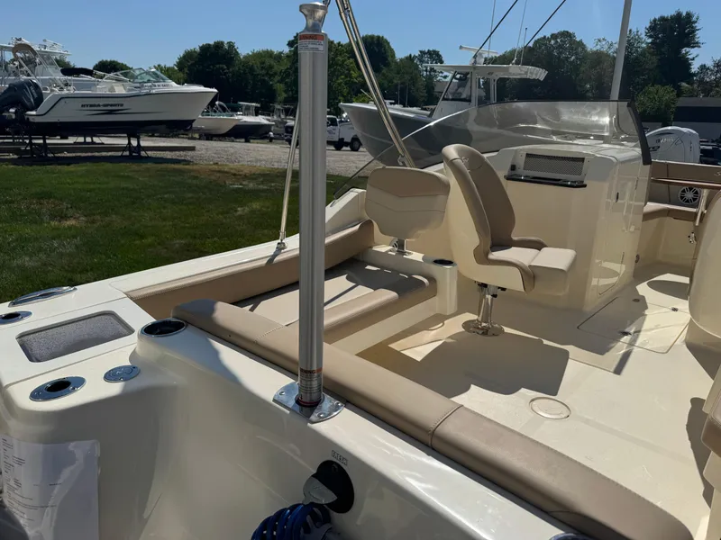 Slide: The Image of 2025 Scout 215 Dorado boat interior with seating and steering area, parked outdoors. - 37