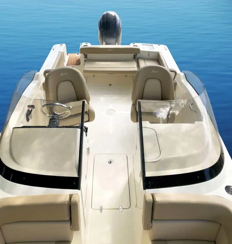 Slide: The Image of 2025 Scout 215 Dorado boat interior with dual seating and steering wheel on calm water. - 48