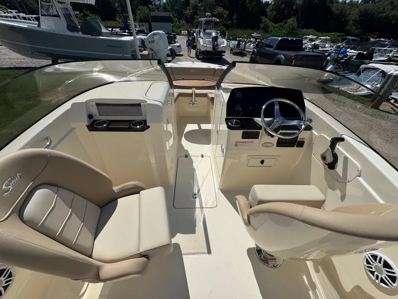 Slide: The Image of 2025 Scout 215 Dorado boat interior with dual seating and steering wheel, docked outdoors. - 7