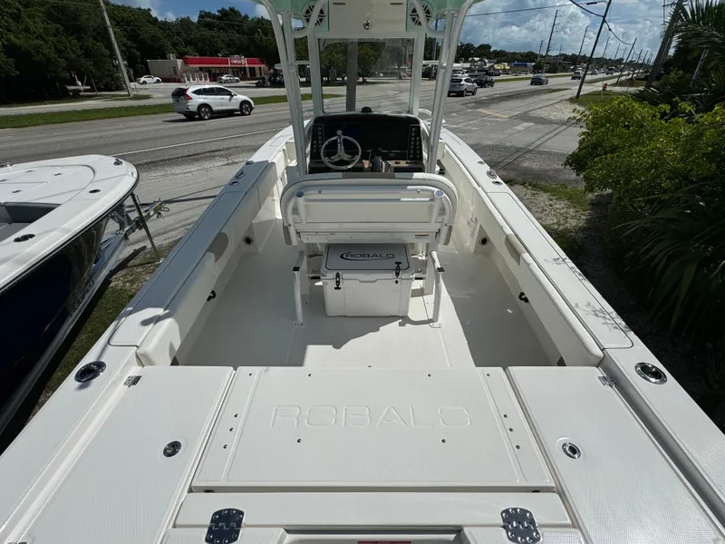 Slide: The Image of 2025 Robalo 266 Cayman SD boat interior with console and seating, parked near a road. - 5