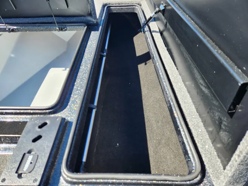 Slide: The Image of 2024 Triton 18 TrX boat storage compartment, open and empty, with black interior lining. - 10