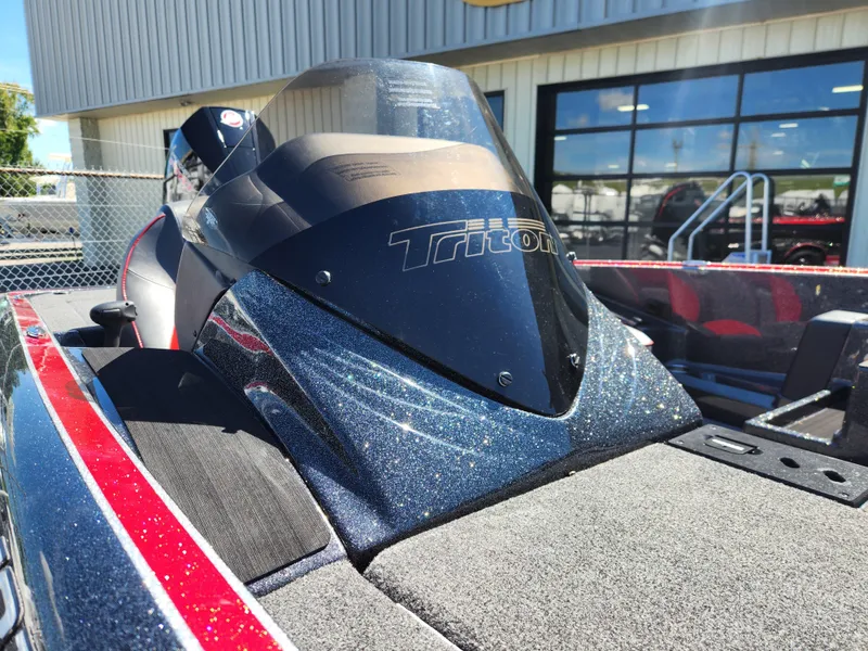 Slide: The Image of 2024 Triton 18 TrX boat with sleek design and windshield, parked outdoors. - 18