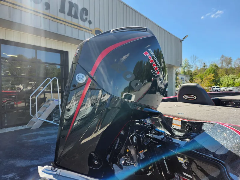 Slide: The Image of 2024 Triton 18 TrX boat engine, sleek black design with red accents, outdoors. - 5