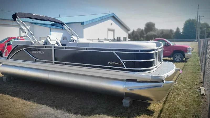 Slide: The Image of 2025 Godfrey SWEETWATER 2286 SB pontoon boat parked outdoors near a red truck. - 3