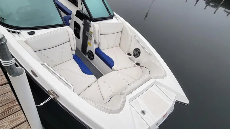 Slide: The Image of 2017 MasterCraft X23 boat with white and blue interior, docked on calm water. - 21
