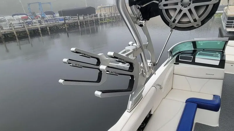Slide: The Image of 2017 MasterCraft X23 boat interior with wakeboard rack and speaker by a calm lake. - 28