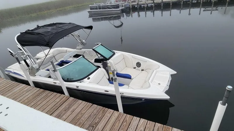 Slide: The Image of 2017 MasterCraft X23 boat docked on calm water with canopy and seating. - 29