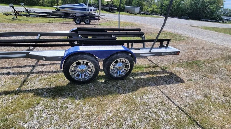 Slide: The Image of Trailer for 2017 MasterCraft X23 boat, featuring dual axles and chrome wheels. - 34