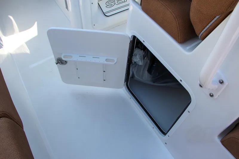 Slide: The Image of 2025 Sea Hunt Ultra 275 SE boat storage compartment with open hatch and brown seating. - 36