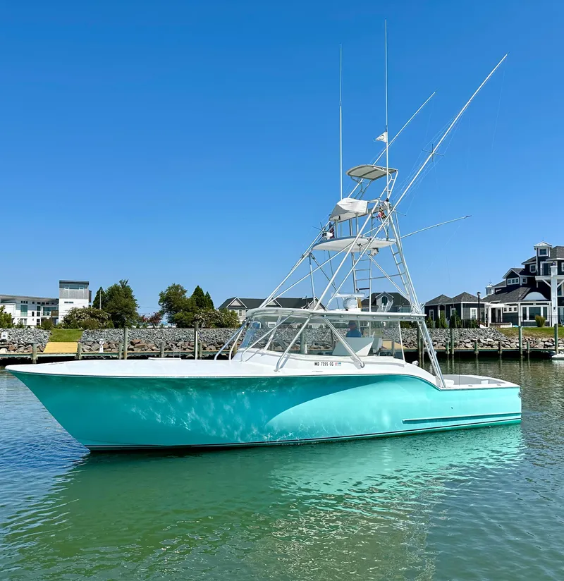 Slide: The Image of 2002 Custom Carolina 40 Express Sportfisherman in marina, turquoise hull, clear sky background. - 12