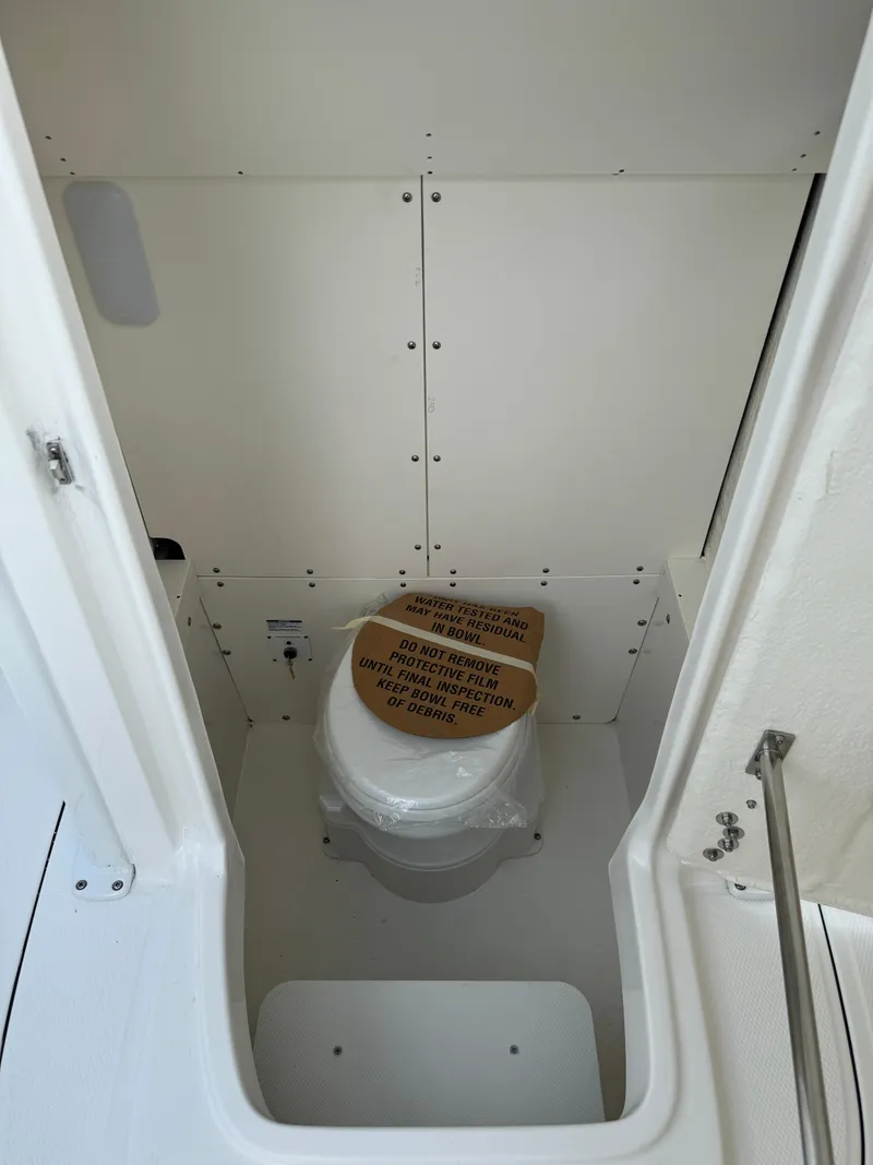 Slide: The Image of 2025 Robalo R230 Center Console boat interior with compact marine toilet. - 18