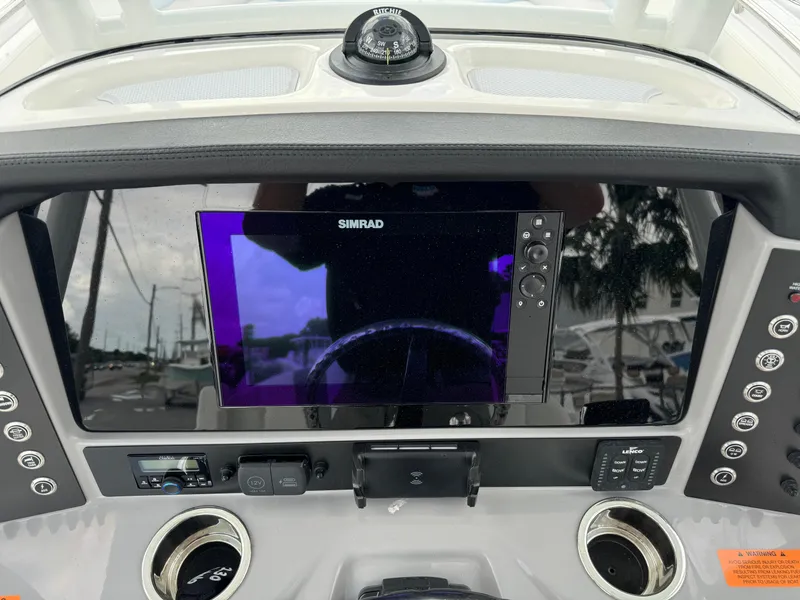 Slide: The Image of 2025 Robalo R230 Center Console dashboard with Simrad display and compass. - 22