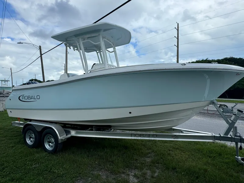 Slide: The Image of 2025 Robalo R230 Center Console boat on trailer, parked on grass under cloudy sky. - 3