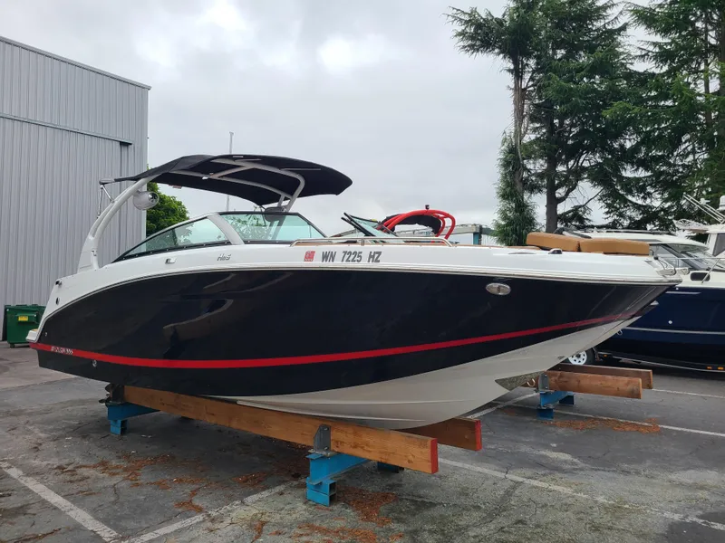 The Image of 2023 Four Winns HD5 boat on display, black and white design, parked outdoors. - 1