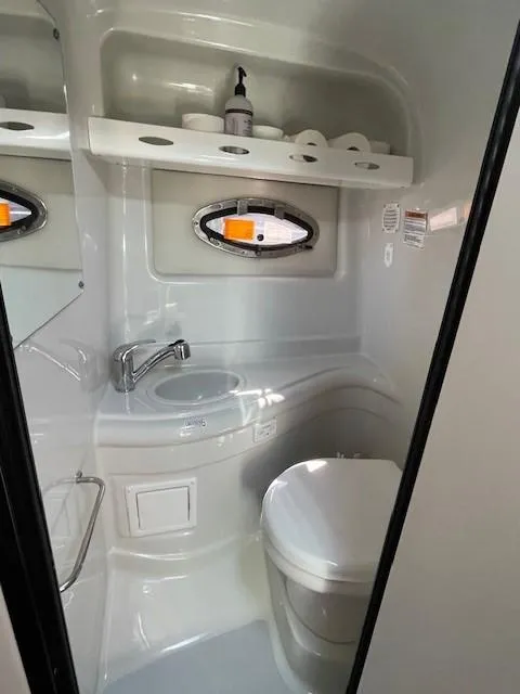 Slide: The Image of 2023 Crownline 270 CR boat bathroom with sink, toilet, and storage shelf. - 19