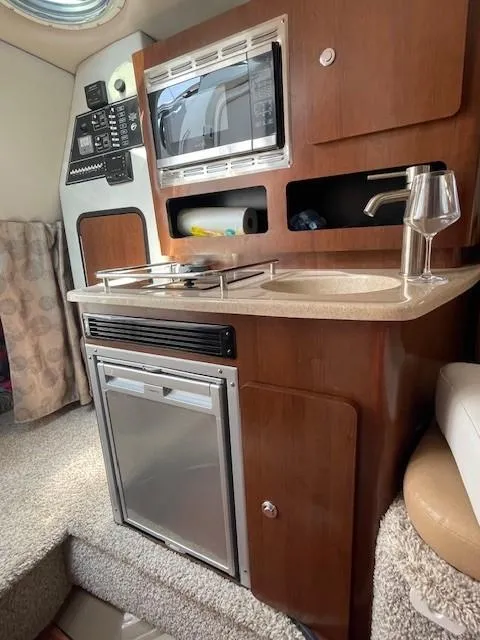 Slide: The Image of 2023 Crownline 270 CR boat interior with kitchenette, microwave, and sink. - 21