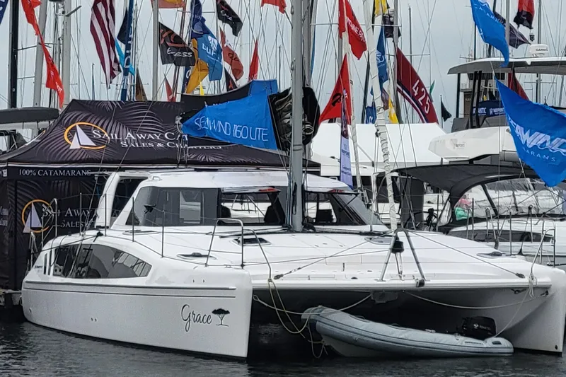 Slide: The Image of 2019 Seawind 1160 Lite catamaran docked and on display at a boat show. - 2