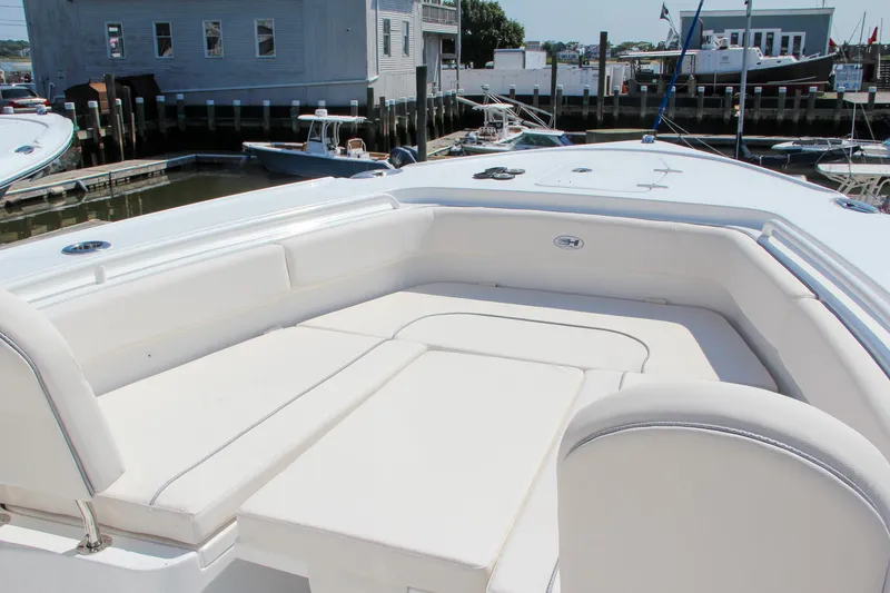 Slide: The Image of 2025 Sea Hunt Ultra 275 SE boat with spacious white seating area in a marina. - 47