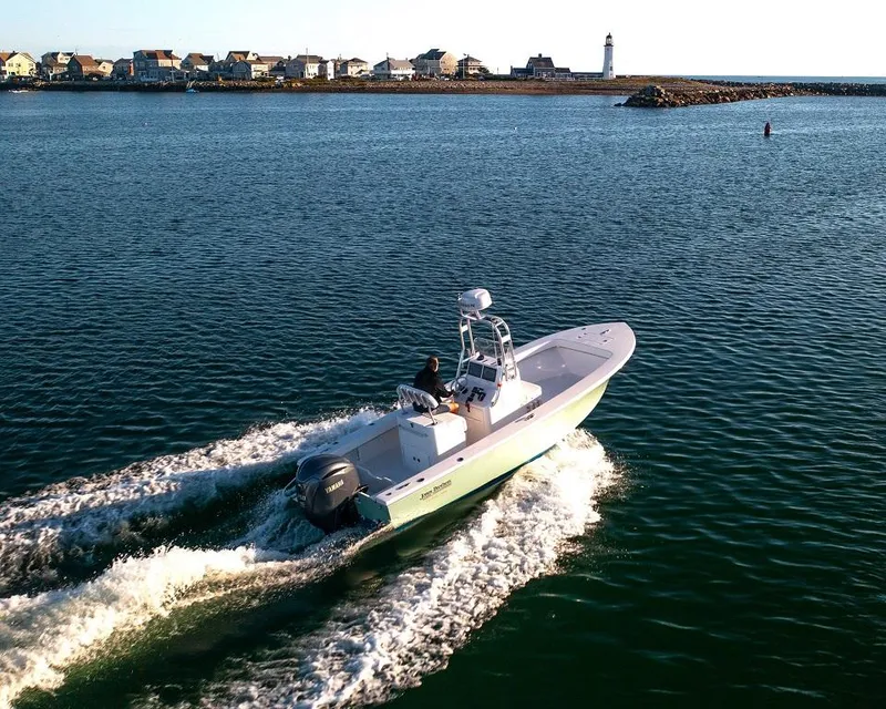 Slide: The Image of 2024 Jones Brothers 23 Cape Fisherman boat cruising near a coastal lighthouse. - 13