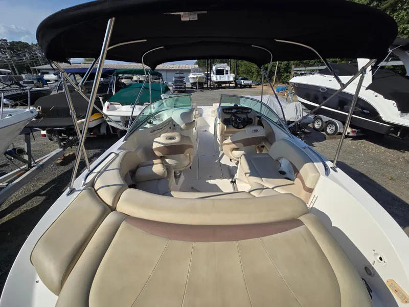Slide: The Image of 2005 Chaparral 236 Sunesta boat with beige seating and black canopy in a marina. - 22