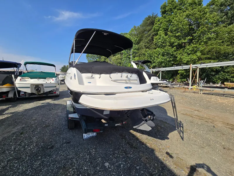 Slide: The Image of 2005 Chaparral 236 Sunesta boat on trailer, parked outdoors with trees in background. - 24