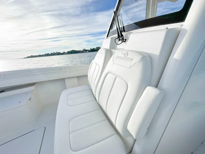 Slide: The Image of 2022 Regulator 28 FS boat with white seating, overlooking calm waters. - 21