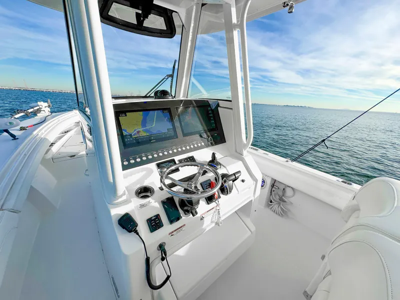 Slide: The Image of 2022 Regulator 28 FS boat cockpit with navigation screens, steering wheel, and ocean view. - 4