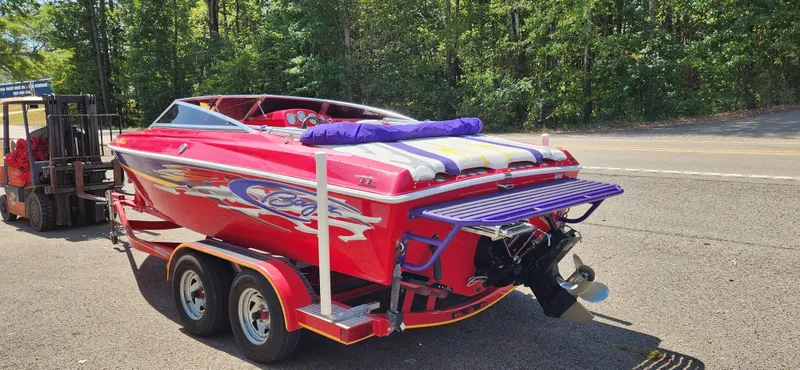 Slide: The Image of Red 2005 Baja 202 Islander boat on trailer, parked near a road with trees in the background. - 3