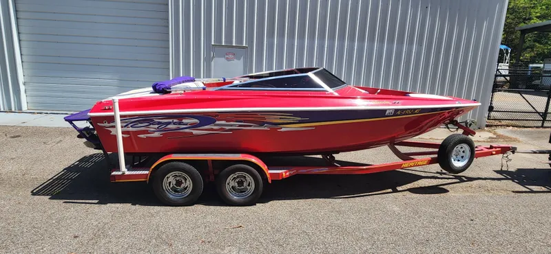 Slide: The Image of Red 2005 Baja 202 Islander speedboat on trailer, parked outside metal building. - 6