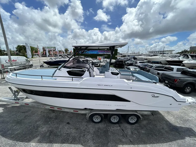 Slide: The Image of 2025 Ranieri 330LX boat on trailer under cloudy sky at marina. - 21